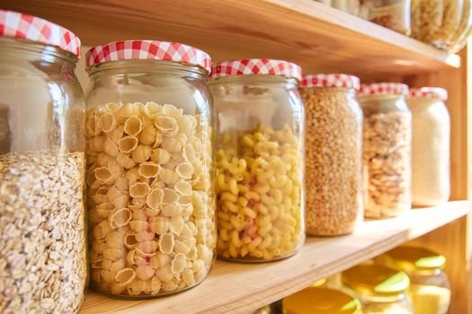Storage of food in the kitchen in the pantry. Cereals, spices, pasta, nuts, flour in jars and containers, kitchen utensils. Cooking at home, stocking food, household
