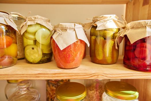Storage of food in the kitchen in pantry. Pickled canned vegetables and fruits on the shelf. Cooking at home, homemade preservation, household