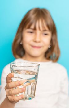 Child girl drinks water from a glass. Selective focus.