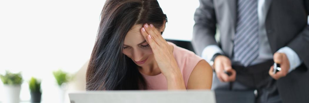 Portrait of woman office worker closing face feeling ashamed because of her boss harassment. Man standing behind with unzip belt. Harassment at workplace