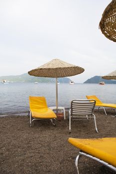 Beautiful yellow chaise lounges and umbrellas made from straw on the beach of Marmaris