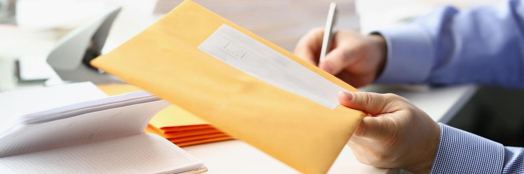 Close-up of businessman give envelope to courier for further delivery to address. Write address on every package with documents. Delivery service concept