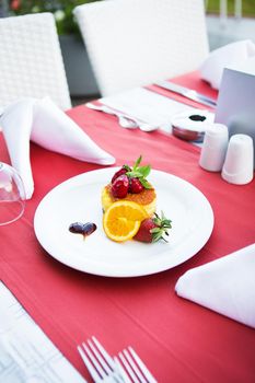 cake-cheesecake decorated with strawberries and orange lies on a white plate