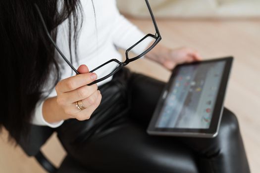 A business woman holds glasses and a tablet in her hands and works outside the office, remote robot. Modern technologies and business