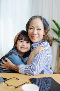 Asian portrait, grandma and granddaughter doing leisure activities and hugging to show their love and care for each other.