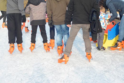 Ice skating teenagers on the skating rink in orange ice skates.