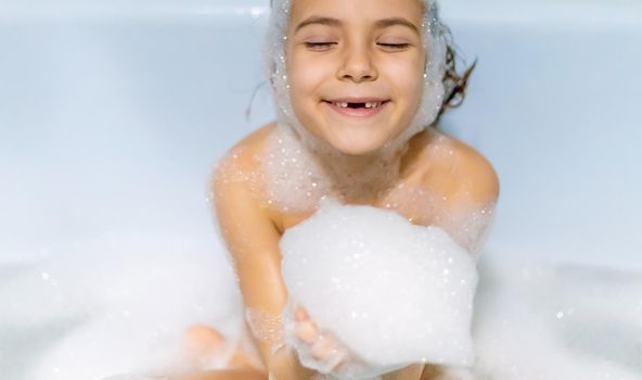 The child bathes in a bathtub soapy water. Selective focus.