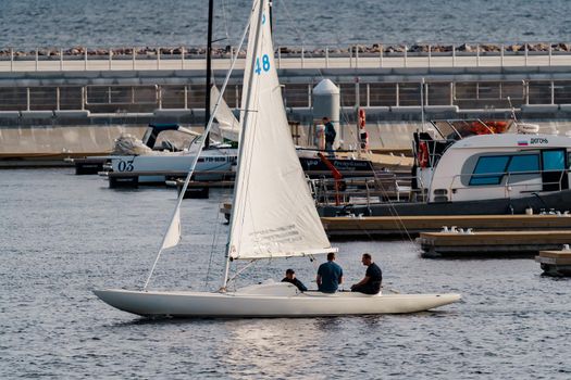 Russia, St. Petersburg, 10 June 2021: A few sailing yachts parked in a new port near the skyscraper of the gas company Gazprom at sunset, pontoons and piers, vintage wooden frigates in the background. High quality photo