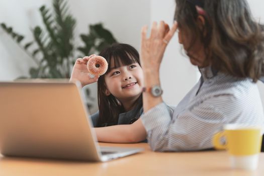 Happy moments of Asian grandmother with her granddaughter talking and playing together. Leisure activities for children at home