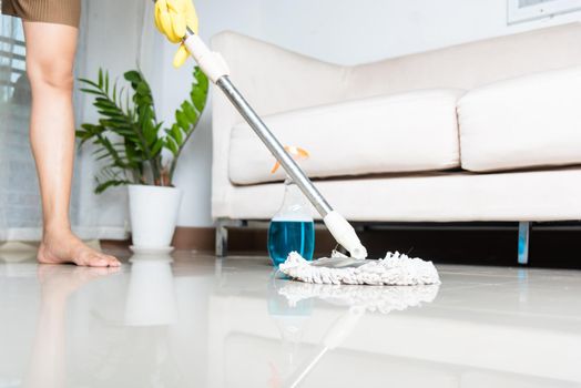 Asian woman washes the floor with a mop and rag indoors, housewife washing floor mopping at home in living room cleaning her home, Professional housekeeping job house cleanup concept