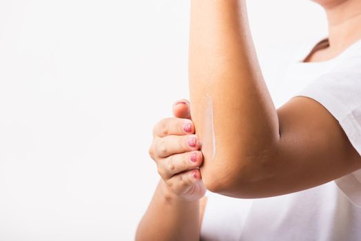 Closeup young Asian woman applies lotion cream on her elbow, studio shot isolated on white background, Healthcare medical and hygiene skin body care concept