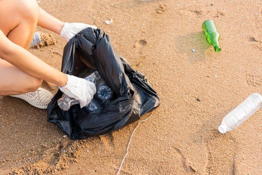 Volunteer woman picking plastic bottle into trash plastic bag black for cleaning the beach, female clean up garbage, Ecology concept and World Environment Day, Save earth concept