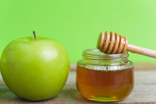 Jewish holiday, Apple Rosh Hashanah, on the photo have honey in jar and green apples on wooden with green background