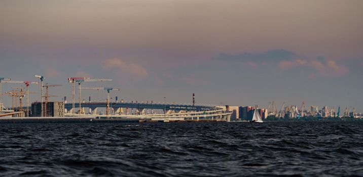 The under construction on the embankment of the Neva River on Vasilievsky island in sunset, highway, bulk island, construction cranes. High quality photo