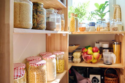 Storage of food in the kitchen in the pantry. Cereals, spices, pasta, nuts, flour in jars and containers, kitchen utensils. Cooking at home, stocking food, household