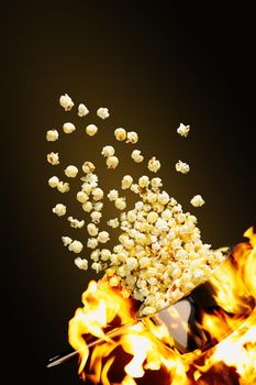 Flying popcorn on a dark background. Hot popcorn flying from pot under fire. cinema popcorn design template. Advertising concept.