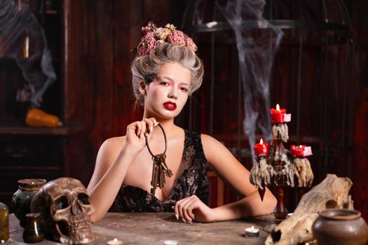 Portrait fortune teller woman reading future on magical scull. Magic and divination. Young beautiful enchanted female witch sitting on the table waiting your desire. Scary Halloween atmosphere