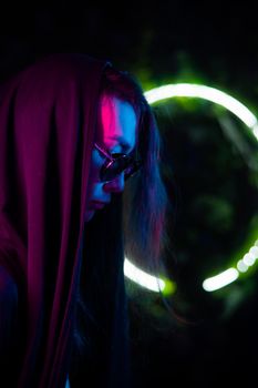 Portrait of asian man in hood and sunglasses in neon light