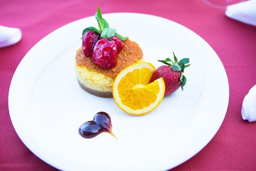 cake-cheesecake decorated with strawberries and orange lies on a white plate