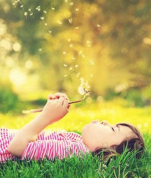 Child girl with dandelions in the park. Selective focus.