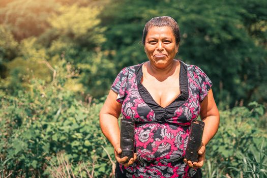 Portrait of a Nicaraguan peasant woman smiling and holding bags of plants in rural Masaya Nicaragua. Photo with copy space.