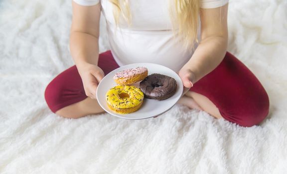 A pregnant woman eats sweet donuts. Selective Focus. Food.