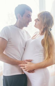 A pregnant woman and a father of a child hug a belly. Selective focus. NATURE.