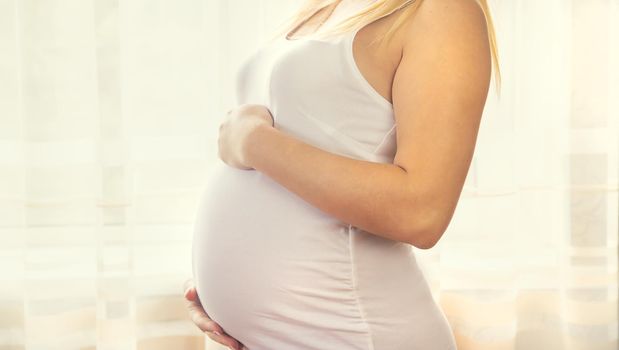 A pregnant woman hugs her belly. Selective focus. People.