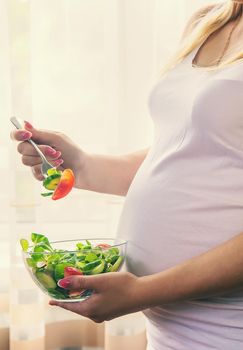 A pregnant woman eats a salad with vegetables. Selective focus. Food.