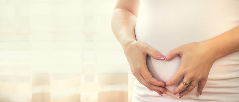 A pregnant woman hugs her belly. Selective focus. People.