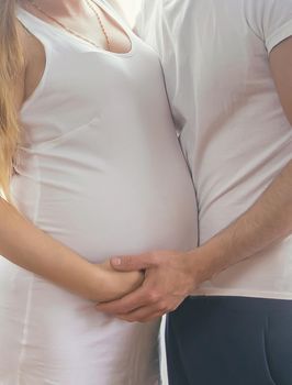 A pregnant woman and a father of a child hug a belly. Selective focus. NATURE.