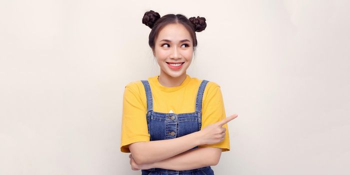 Portrait of a young happy woman pointing finger away isolated on a white background