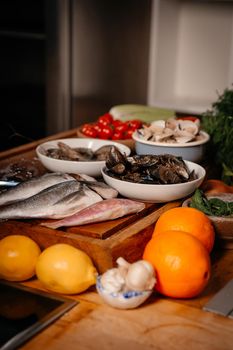 Sea bream, garlic, shrimp and shells on the table next to vegetables and fruit. Ingredients for making a delicious soup. Fine cuisine.