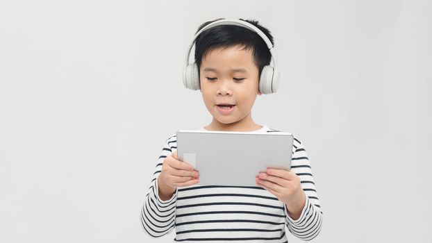 technology - a lovely young pupil standing with his tablet wearing headphones