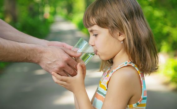 The father gives the child a glass of fresh water. Selective focus. nature.