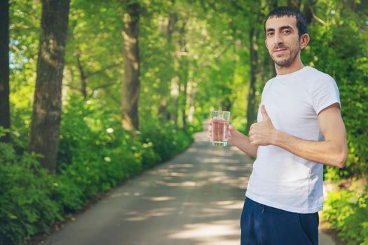 A man drinks water from a glass on the nature. Selective focus. Drink.