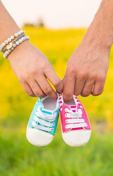 pregnant woman and man hold baby shoes. Selective focus. nature.