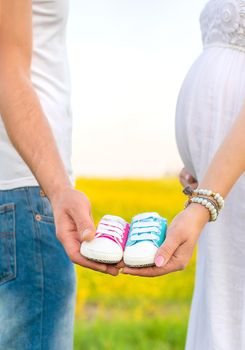 pregnant woman and man hold baby shoes. Selective focus. nature.