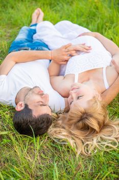 Pregnant woman and man photo shoot lie on the grass. Selective focus.