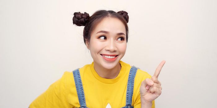 Smiling attractive young woman pointing away over white background