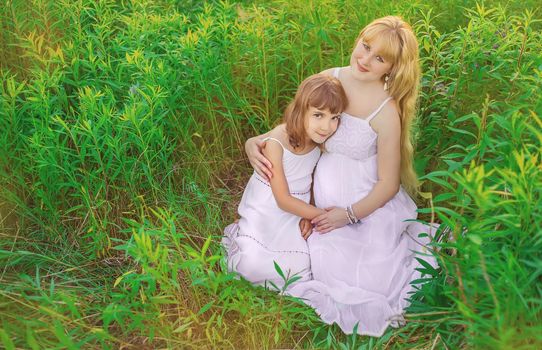 Child photo session in a lupine field with a pregnant mother. Selective focus.