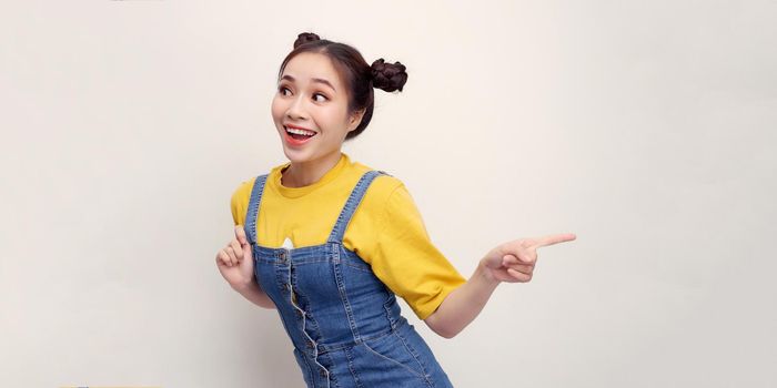 Portrait of Asian beautiful young woman pointing one hand with finger on upper left side with smile face. Advertisement & presentation concept.