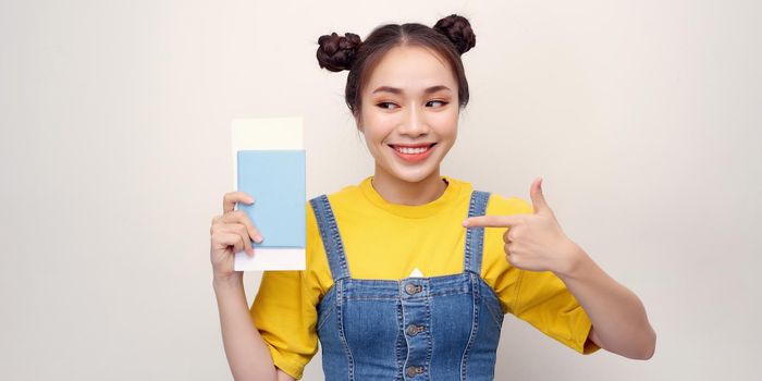 Young beautiful asian woman holding passport  smiling happy pointing with hand and finger