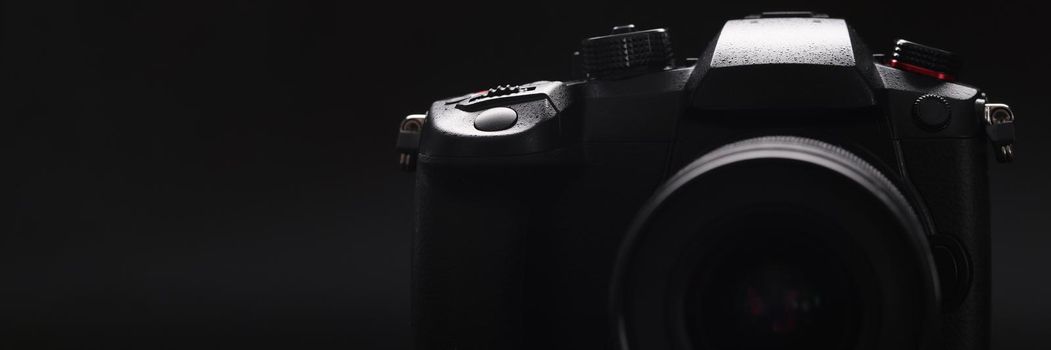 New photo camera on black background closeup. Sale of photographic equipment concept