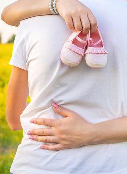 pregnant woman and man hold baby shoes. Selective focus. nature.