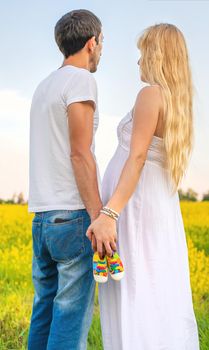 pregnant woman and man hold baby shoes. Selective focus. nature.