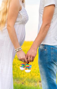 pregnant woman and man hold baby shoes. Selective focus. nature.