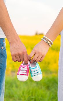 pregnant woman and man hold baby shoes. Selective focus. nature.