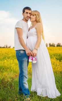 pregnant woman and man hold baby shoes. Selective focus. nature.