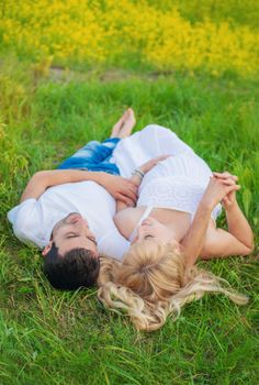 Pregnant woman and man photo shoot lie on the grass. Selective focus.